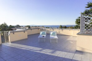 A rooftop terrace with two sun loungers, a view of the sea, and a distant mountain range. - Summer Colors rooms & apartments (Meta)