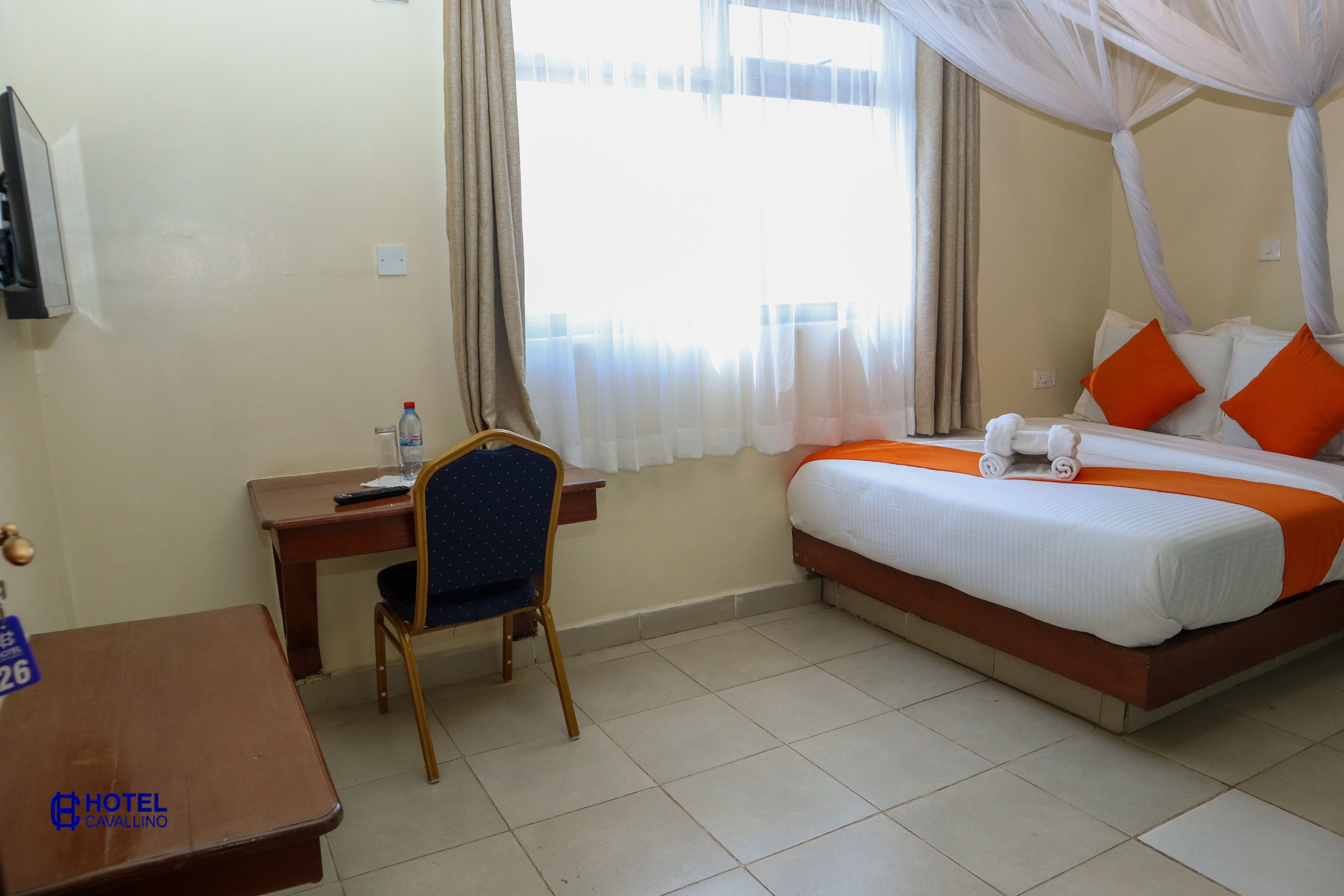 A hotel room with a bed, a desk, a chair, and a television.