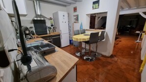 A compact kitchen with a microwave, toaster, and sink. There is a dining area with a table and chairs. - La Chaumière aux Lamas (Goupil-Othon)