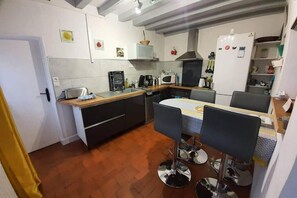 A compact kitchen with a dining area, featuring a built-in oven, microwave, and a refrigerator.