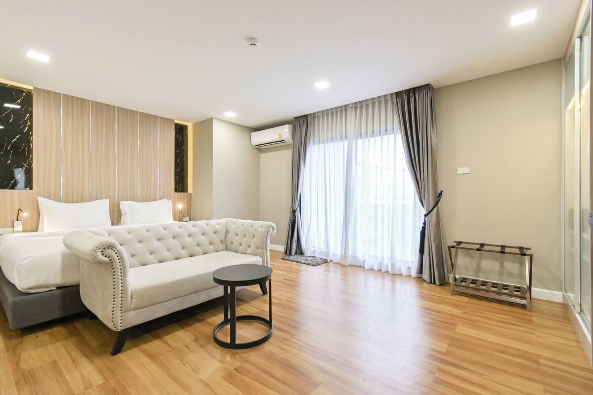 A modern hotel room with a sofa, a round table, and a built-in air conditioning unit.