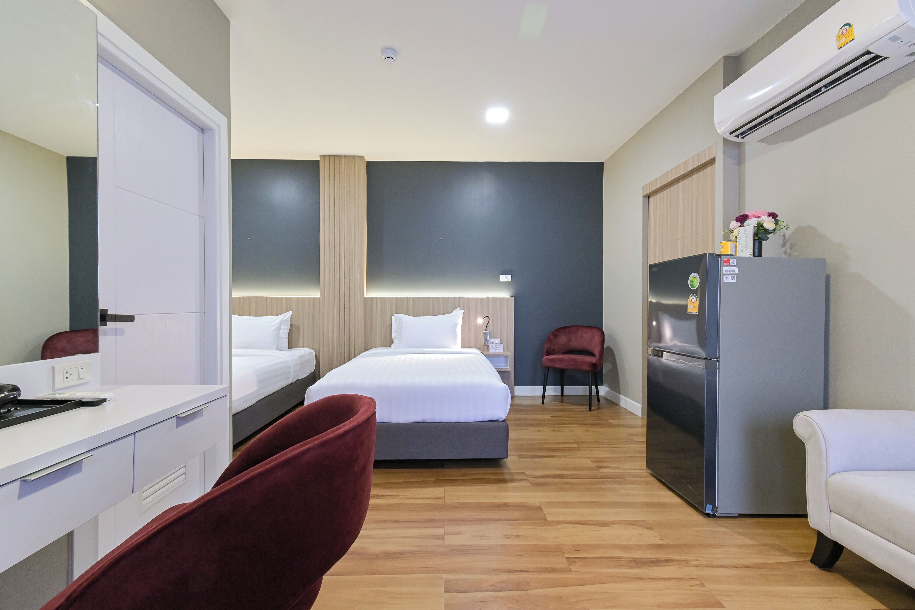 Una habitación de hotel moderna con cama, escritorio, silla, refrigerador y aire acondicionado.