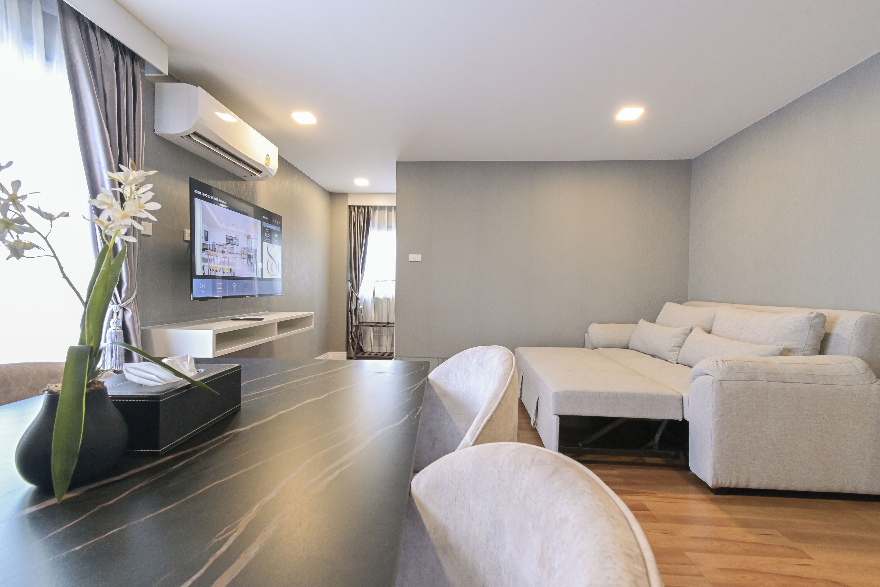Una sala de estar moderna con un sofá, un televisor de pantalla plana y una planta en maceta.