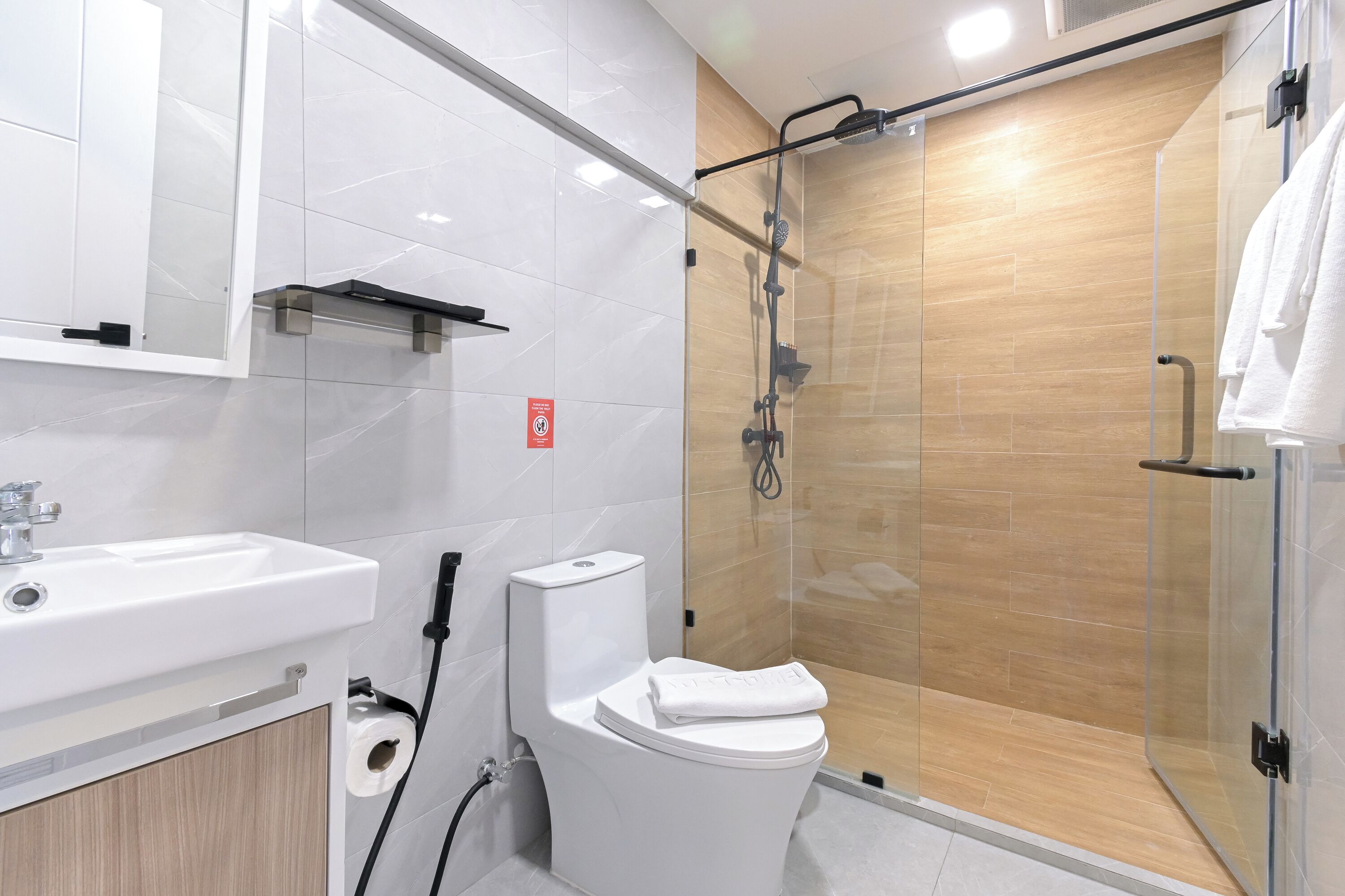 Un baño moderno con cabina de ducha de vidrio, un lavamanos blanco y un inodoro.