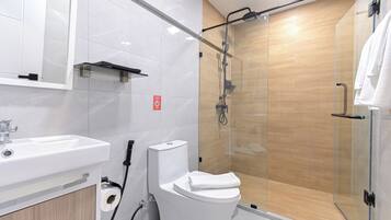 Un baño moderno con cabina de ducha de vidrio, un lavamanos blanco y un inodoro.