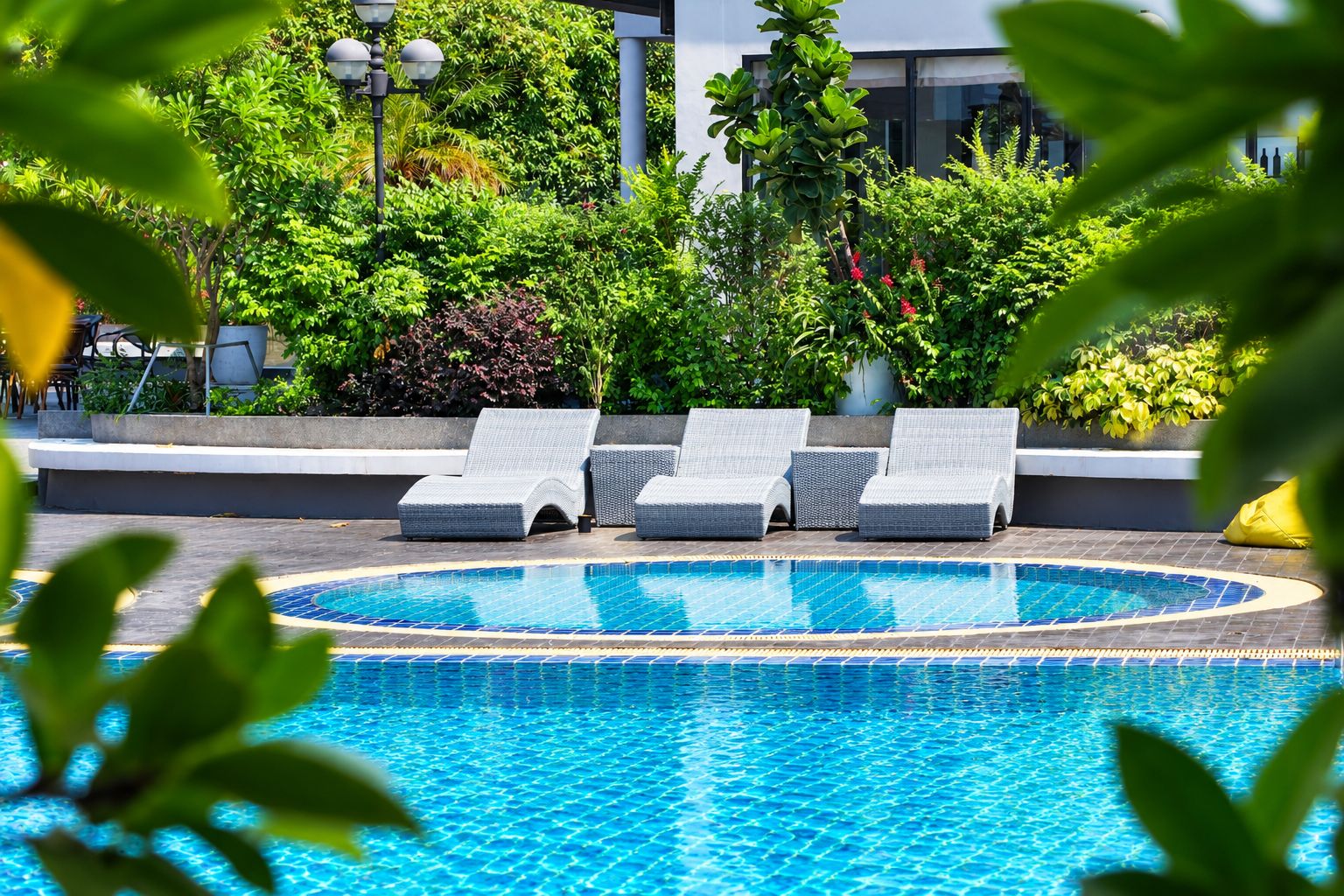 Una piscina con sillas de descanso y un jardín.