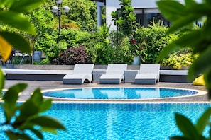 A swimming pool with lounge chairs and a garden area.