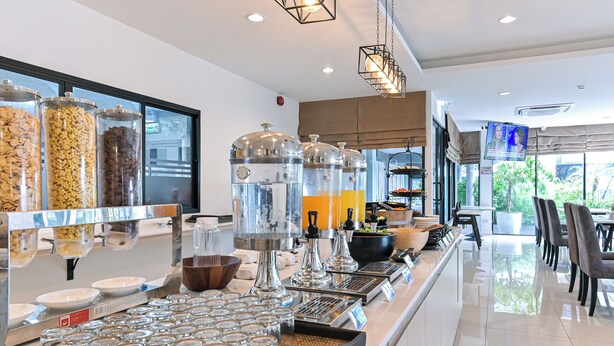A breakfast bar with various food dispensers, a coffee machine, and a TV screen. - Shewin de Bangkok (Bangkok)