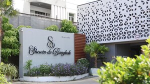 A sign for Shewin de Bangkok with a modern building in the background. - Shewin de Bangkok (Bangkok)