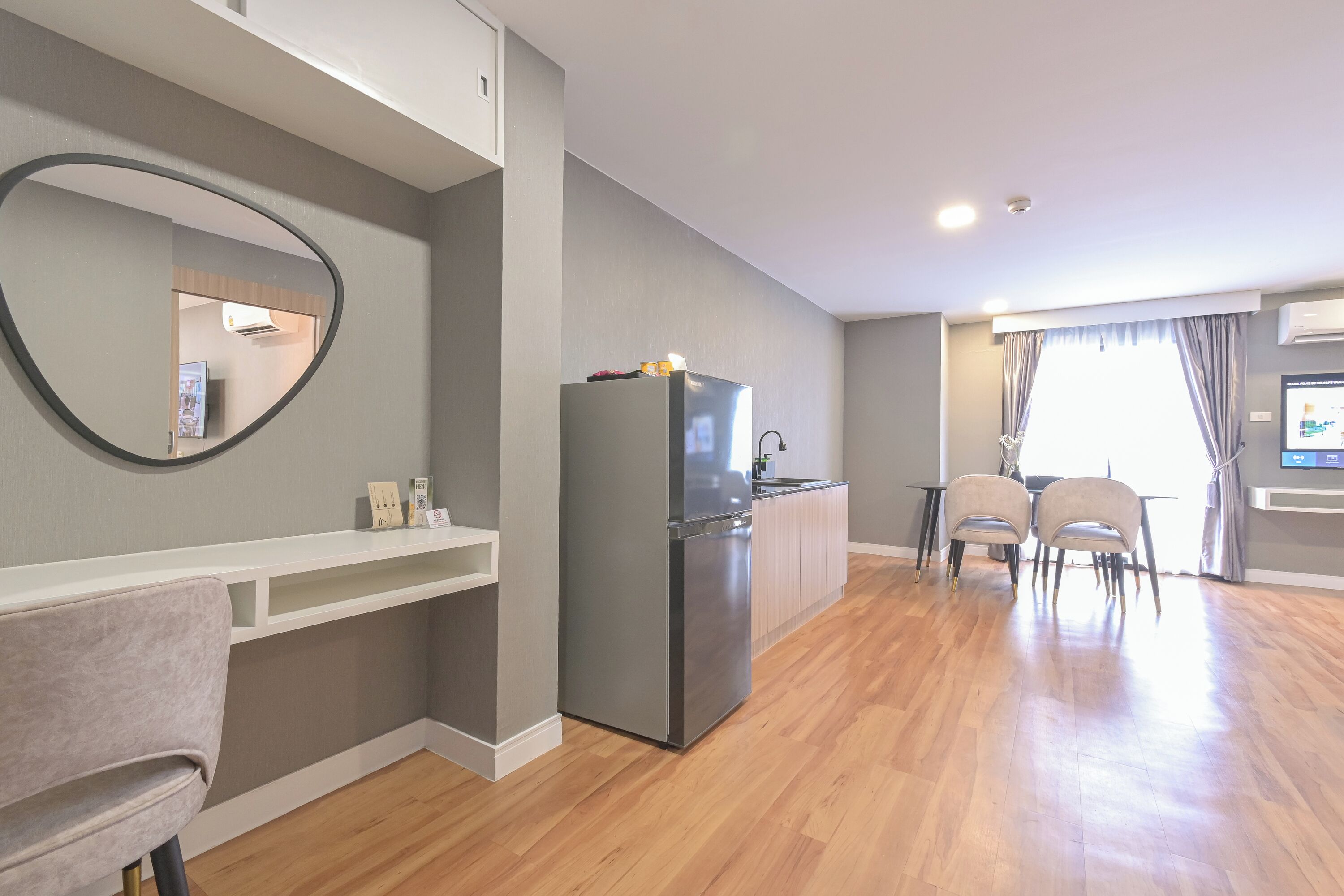 A modern kitchen with a built-in refrigerator, a dining area with a table and chairs, and a large mirror on the wall.
