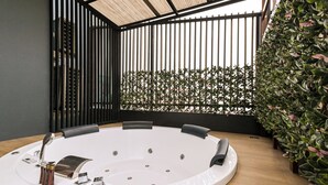 A modern spa room with a circular hot tub, black metal partitions, and lush green plants. - Shewin de Bangkok (Bangkok)