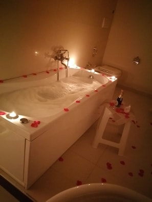 Una bañera con pétalos de rosa y una botella de champán.
