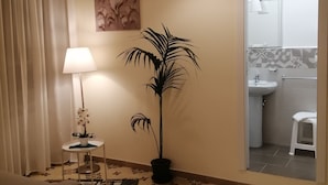 Una sala de estar con un sofá, una lámpara, una planta en maceta y un suelo estampado.