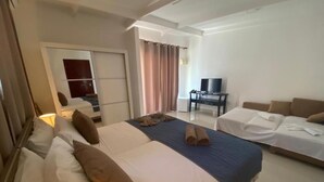 Ein Hotelzimmer mit einem großen Bett, einem Schreibtisch mit Stuhl, einem Fernseher und einer Schiebetür.