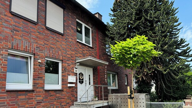 Een gebouw van rode baksteen met een witte deur, ramen en een klein portaal.