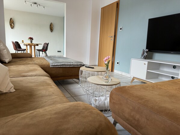 Ein modernes Wohnzimmer mit einer Couch, einem Couchtisch und einem Fernseher.