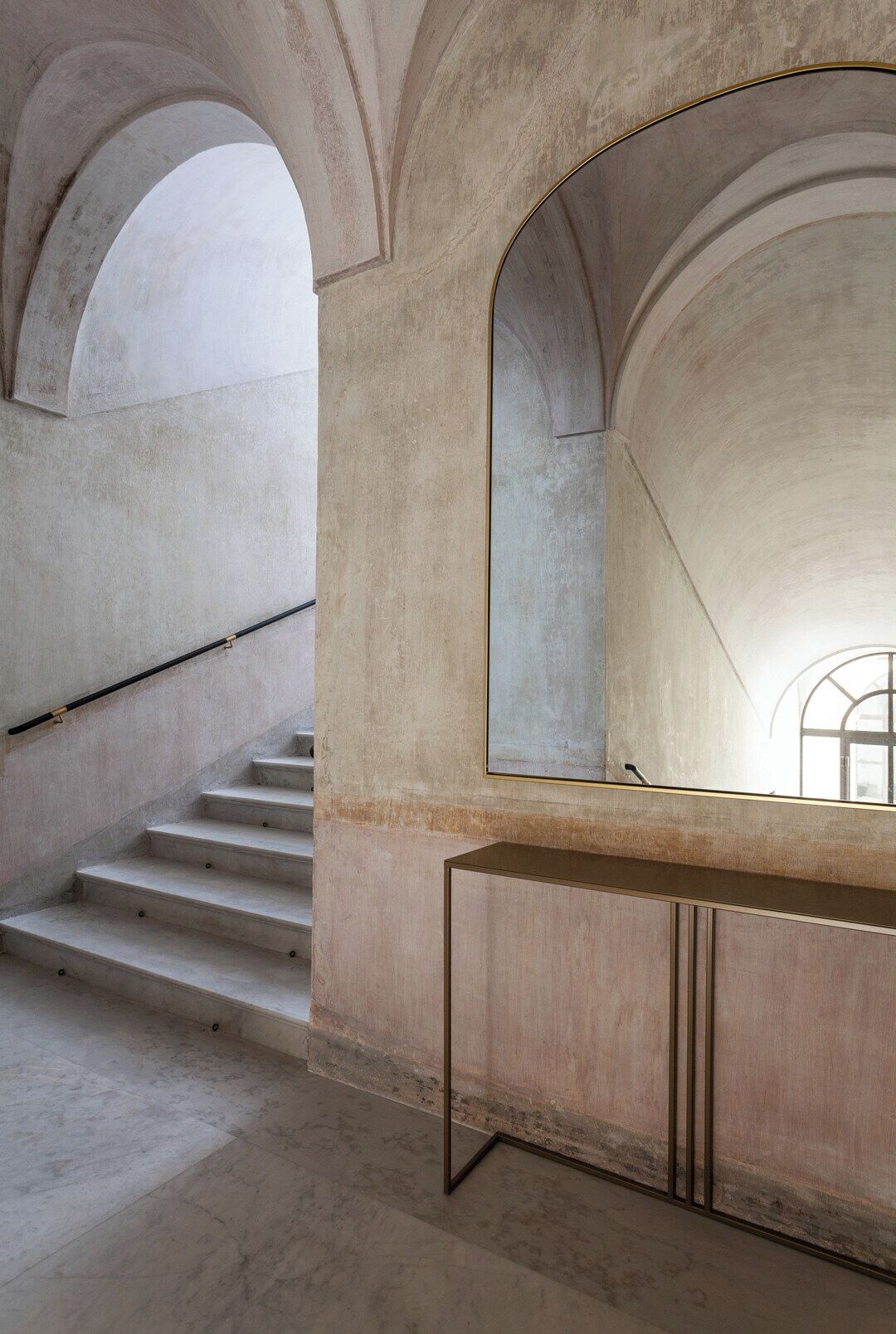 Eine Treppe mit minimalistischem Design, ein großer Spiegel und ein schlichter Konsolentisch.