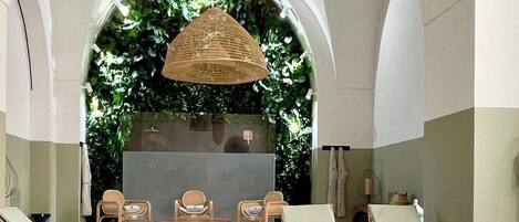A poolside area with lounge chairs, a small table, and a hanging wicker light fixture.
