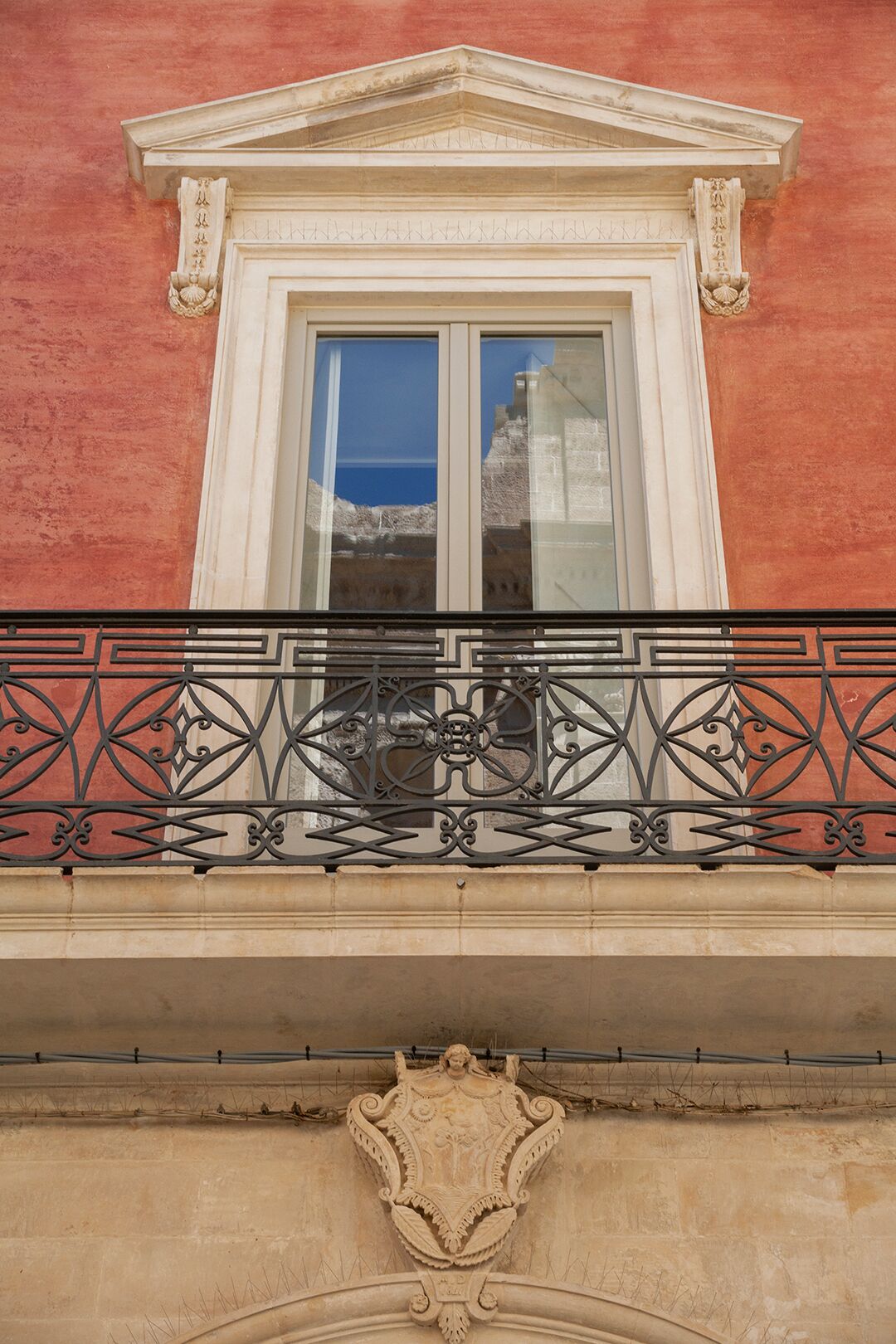A building facade with a classical window and ornate balcony railing.