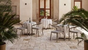 Un patio con mesas y sillas, techos abovedados y luces colgantes.