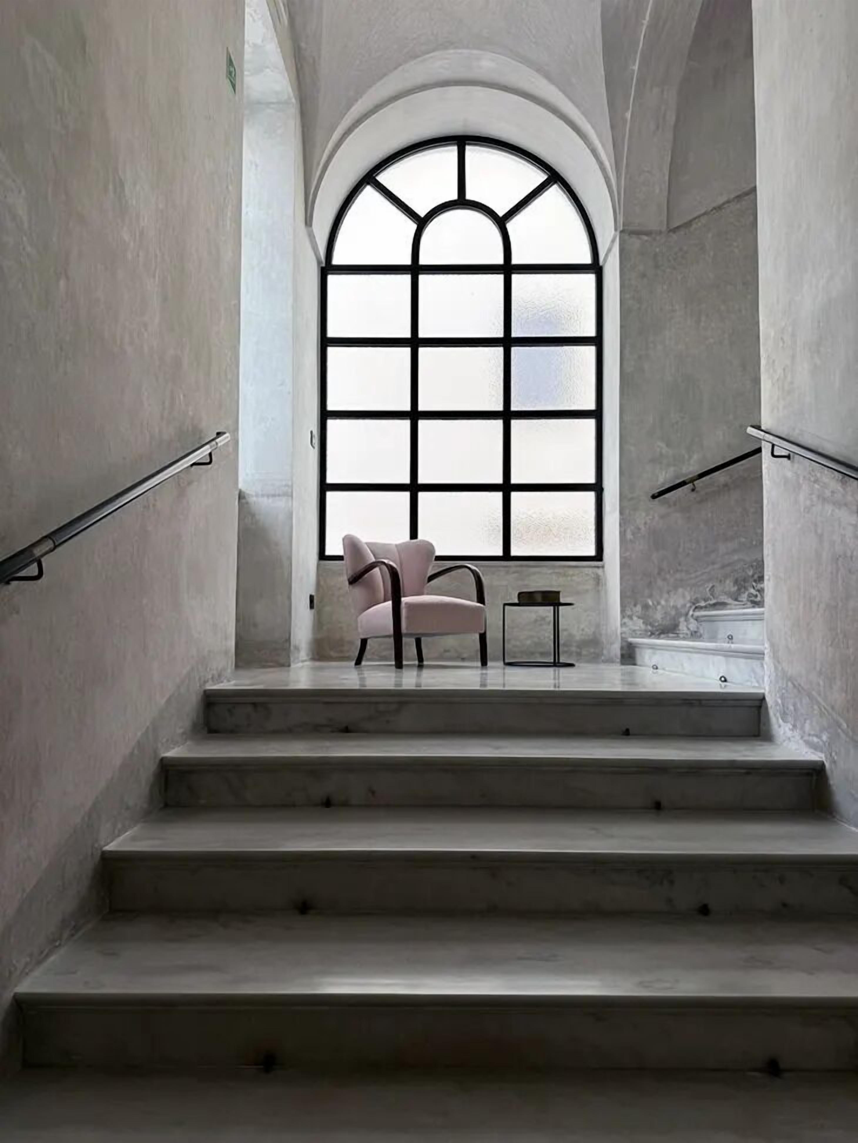 Una escalera de diseño moderno que conduce a una habitación con un amplio ventanal en arco.
