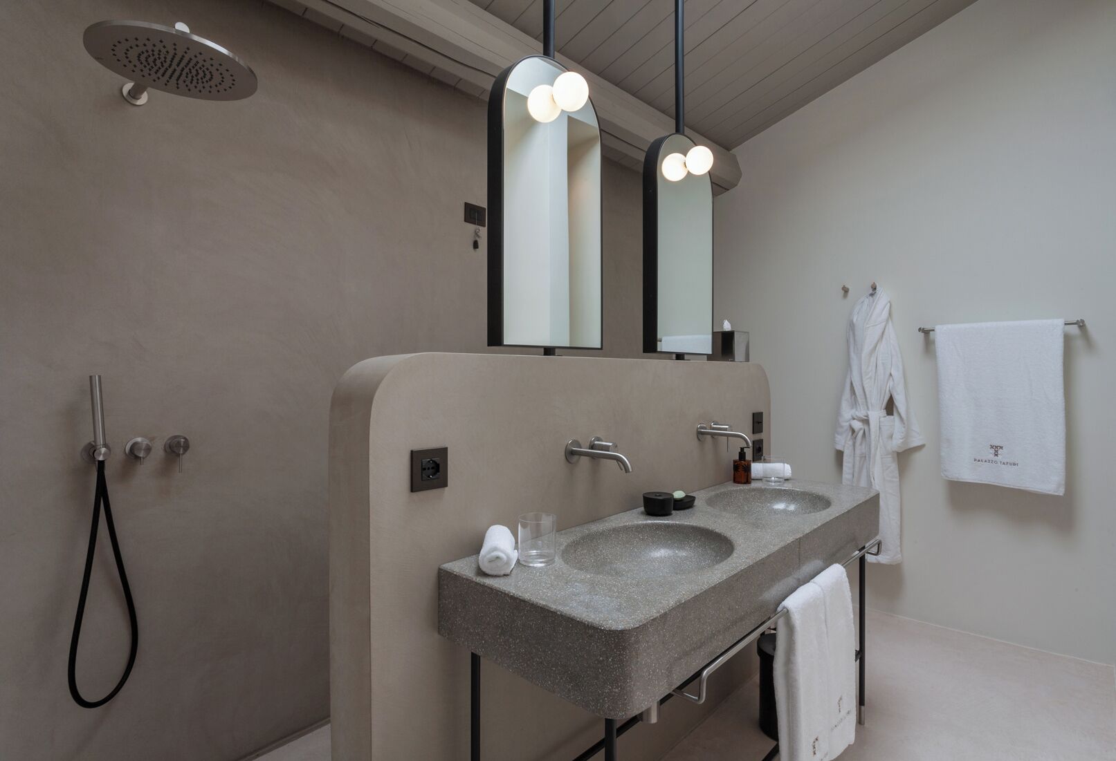 Ein modernes Badezimmer mit Dusche, zwei Waschbecken und einem großen Spiegel.