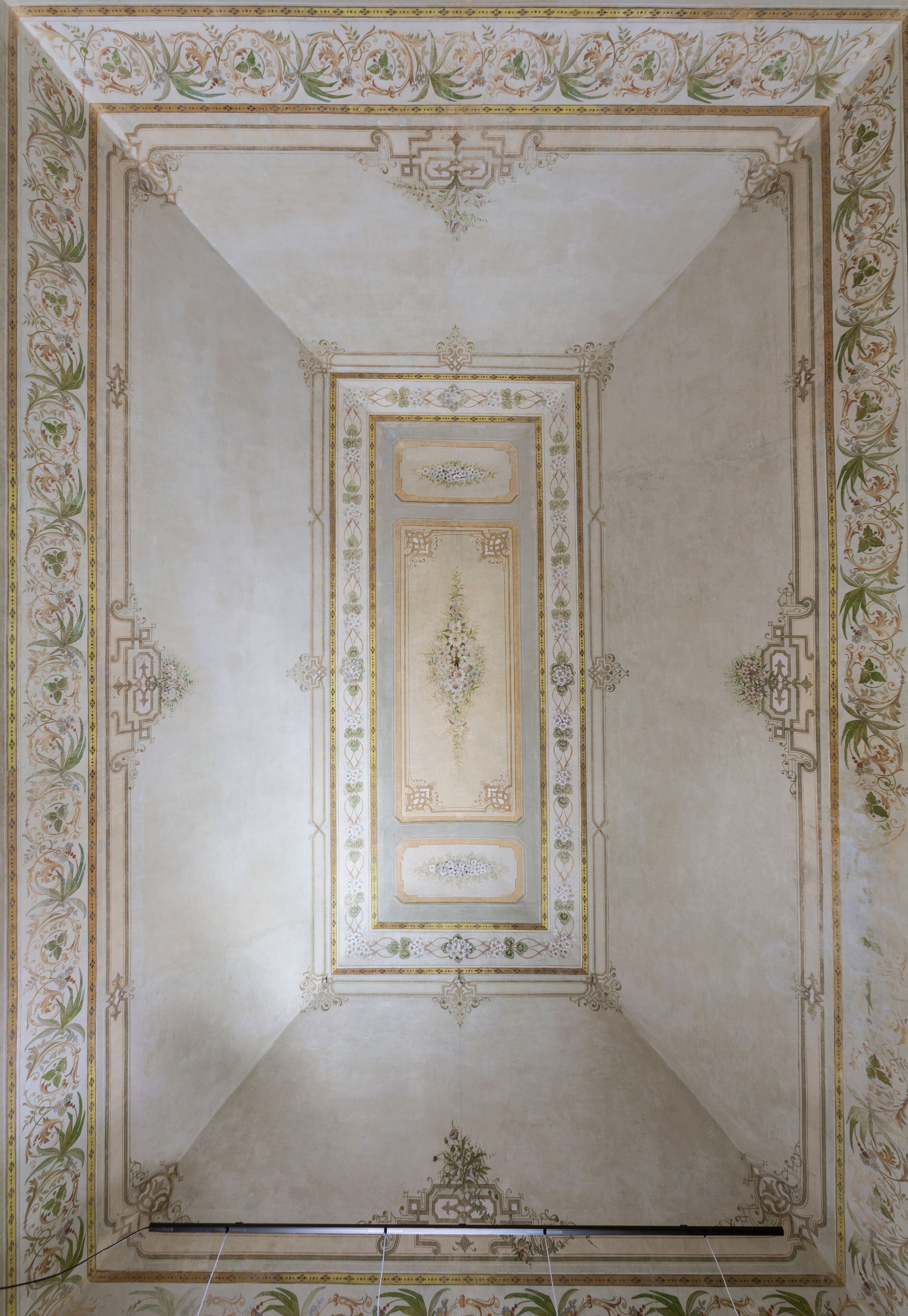 A ceiling with ornate floral and geometric patterns, a central medallion, and a symmetrical design.