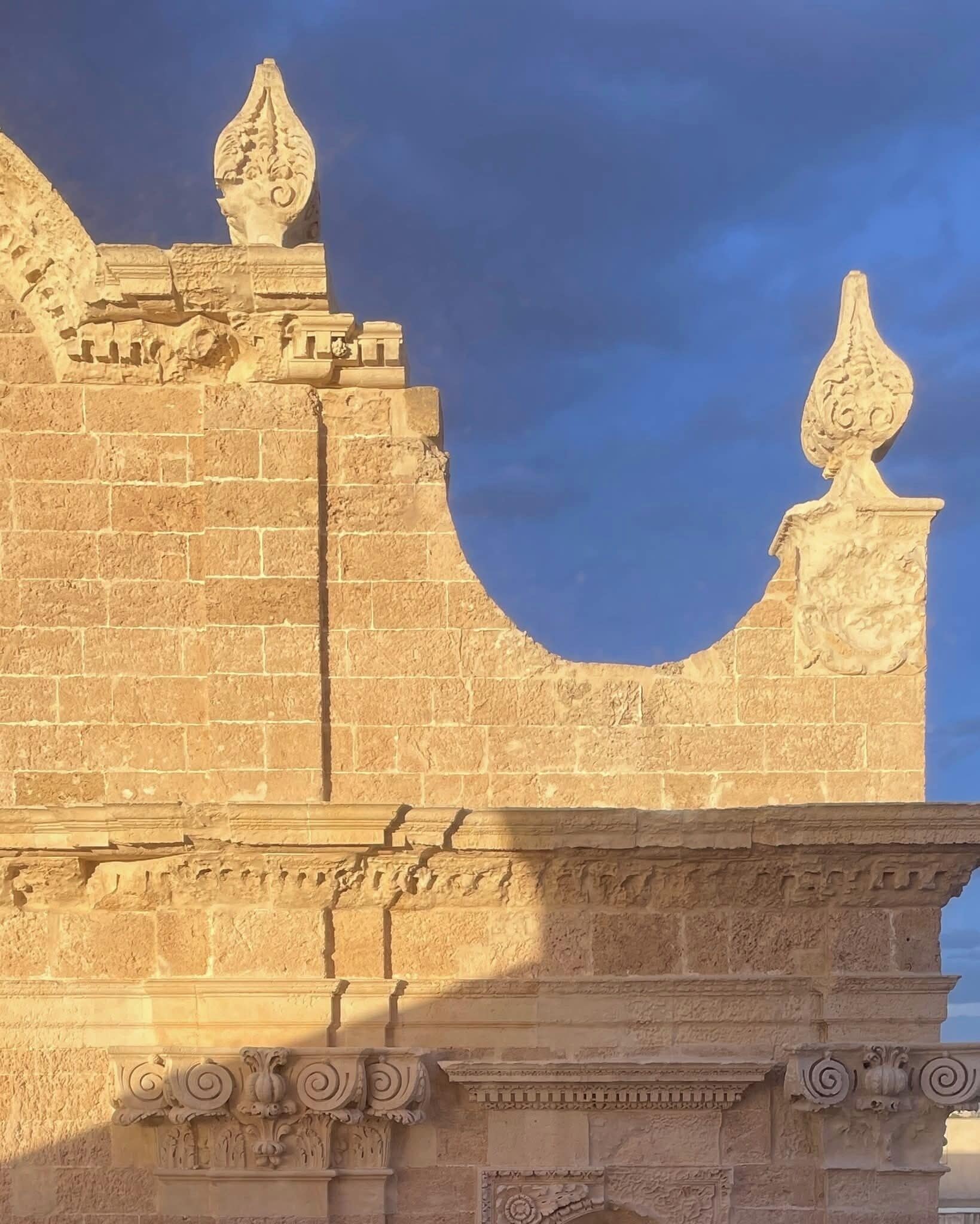 A stone structure with intricate carvings and a pointed archway.