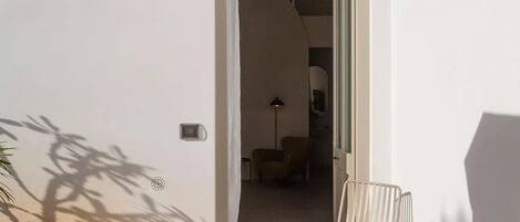 Un espace patio comprenant deux chaises en métal, une petite table et une porte donnant sur un espace intérieur.