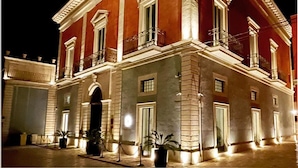 Un edificio grande e histórico con fachada simétrica, múltiples ventanas y una entrada central.