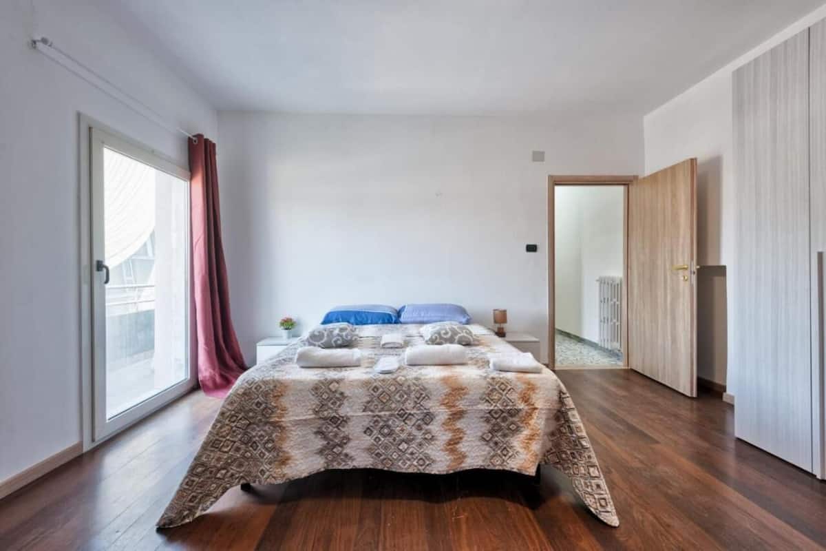 A bedroom with a large bed, a sliding door, and a wardrobe.