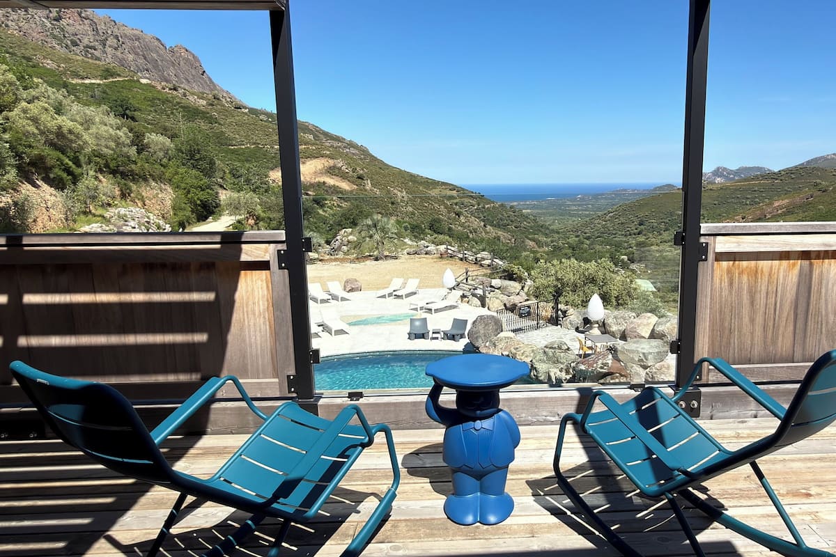 A poolside area with lounge chairs and a view of a mountainous landscape.