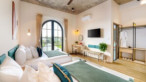 Habitación de hotel con dos camas, un escritorio, un televisor y un zapatero.