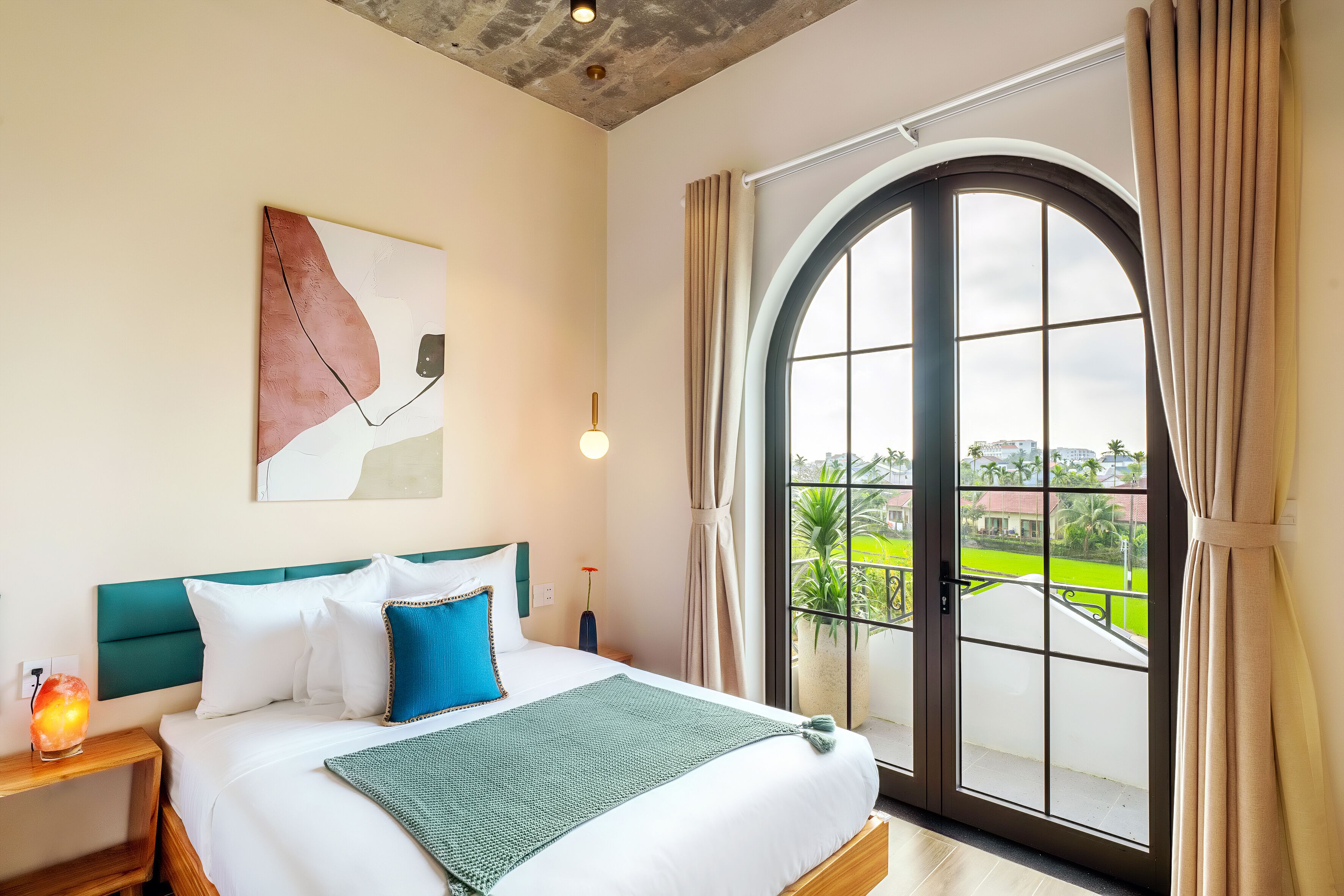 A bedroom with a large bed, a view of a green landscape through a glass door, and a modern ceiling design.