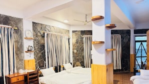 Een moderne hotelkamer met een stenen muur, een bed met wit beddengoed, een houten bureau en een klein plankje met een waterkoker.