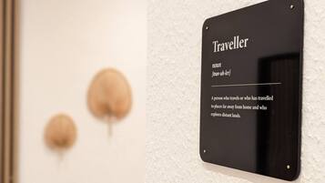 Ein schwarzes Schild an einer weißen Wand mit dem Wort 'Traveller' und einer Definition.