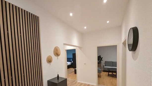 Een moderne hal met een houten vloer, een zwarte wastafel en een spiegel aan de muur.