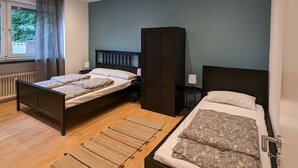 Een slaapkamer met twee bedden, een kledingkast en een raam met gordijnen.