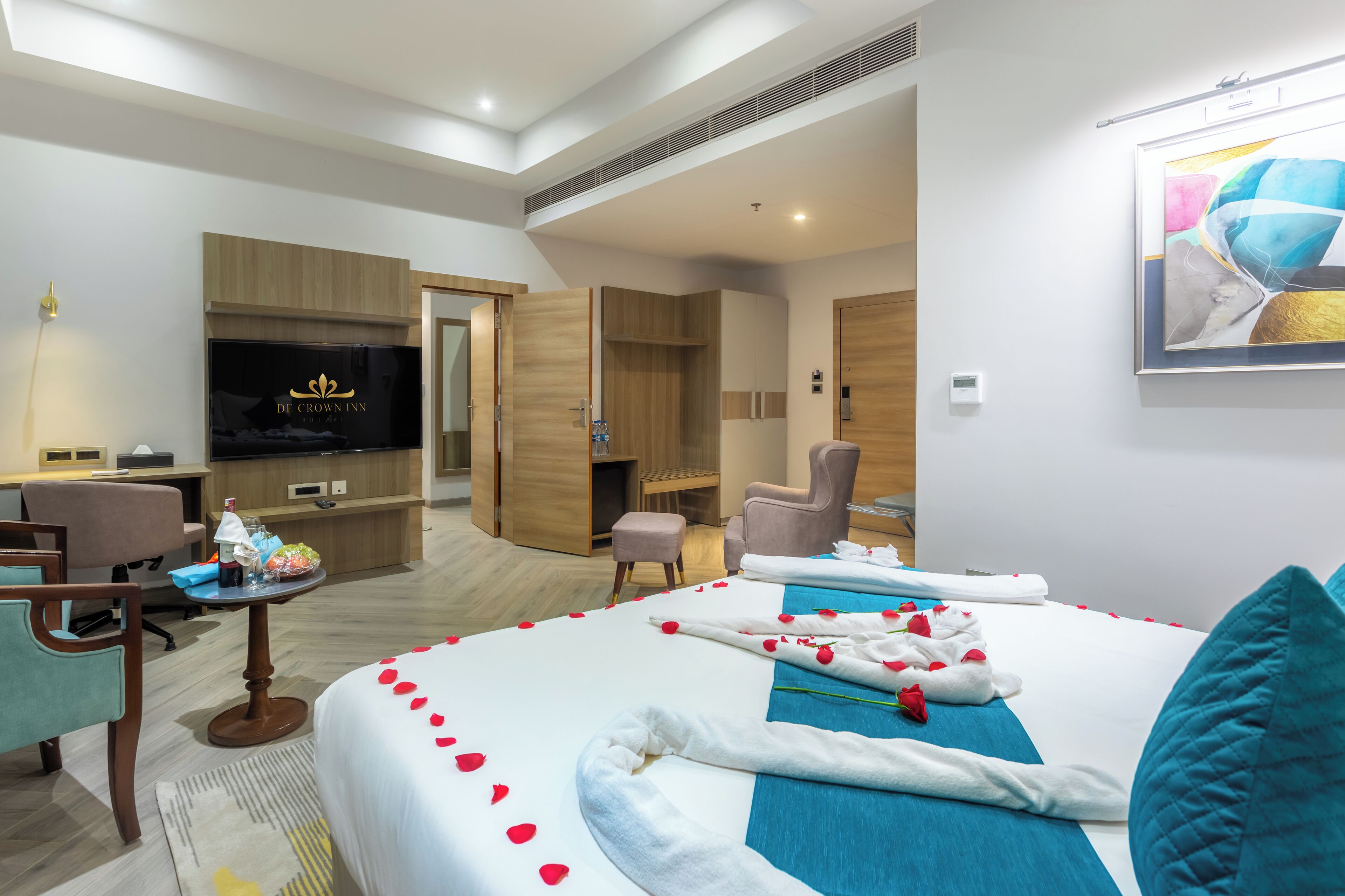 Quarto de hotel com cama, escrivaninha, televisão e guarda-roupa.