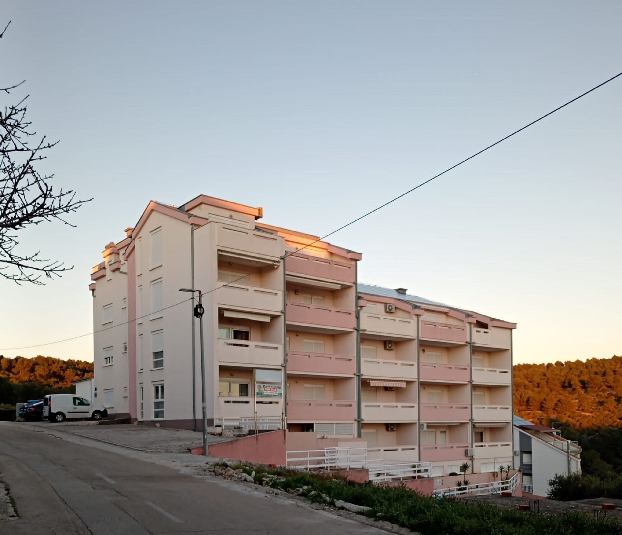 Un immeuble à plusieurs étages doté de balcons, d’un espace de stationnement et d’une enseigne indiquant une vente.