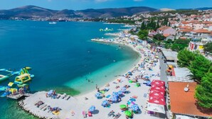 A coastal town with a beach, clear waters, and a dock with inflatable structures.
