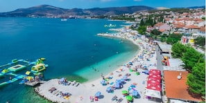 Un pueblo costero con una playa, aguas cristalinas y un muelle con estructuras inflables.