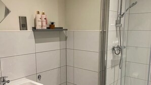 A modern bathroom with a white sink, toilet, and a glass-enclosed shower area.