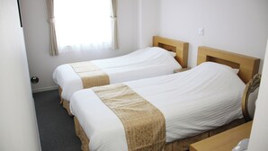A hotel room with two single beds, a wooden headboard, a small wooden desk, and a window with curtains. - Business Hotel Yamate Inn (Kofu)