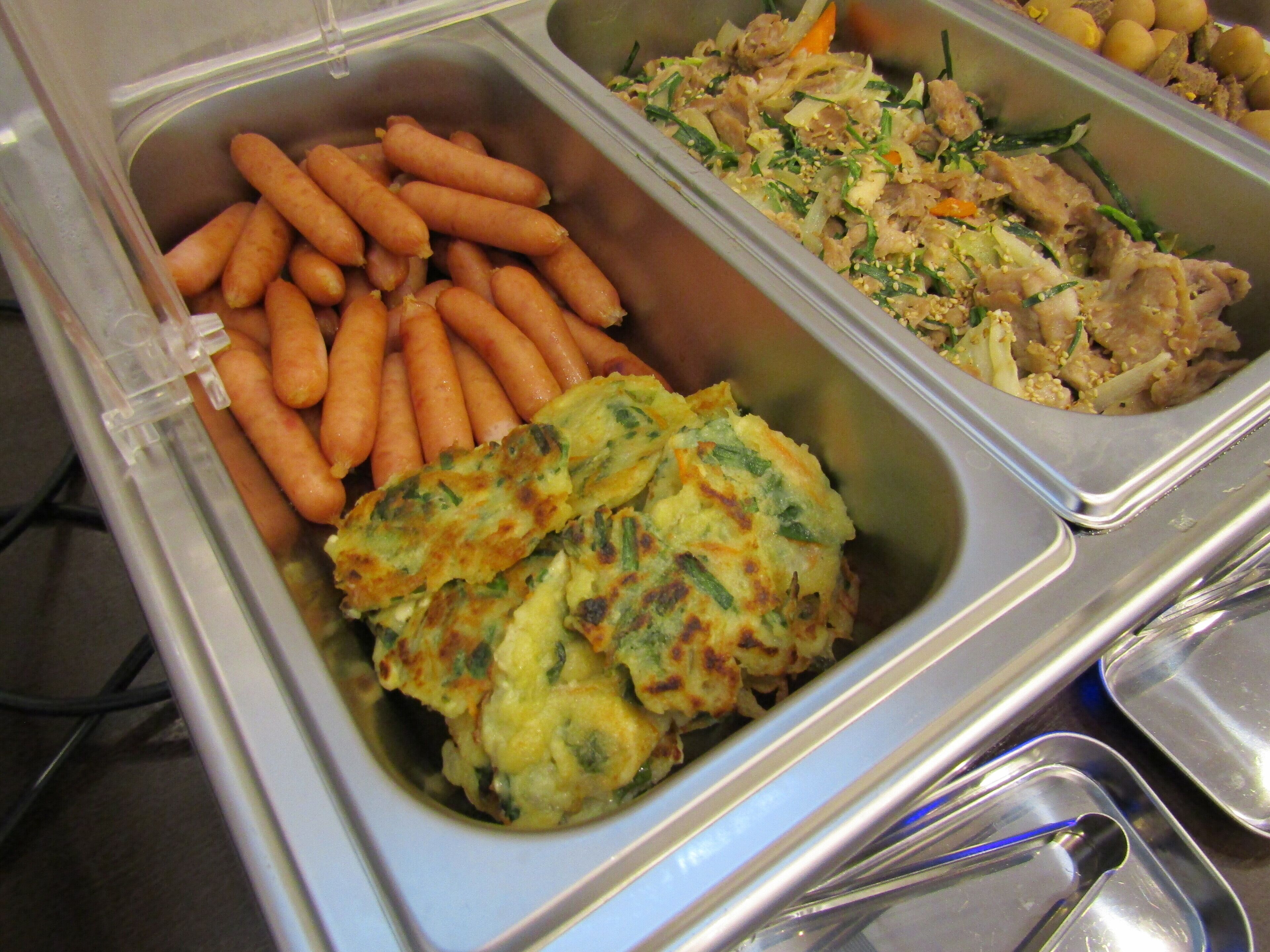 Buffetissa on tarjolla monenlaista ruokaa, kuten porkkanoita, kasvisruoka ja liharuoka.