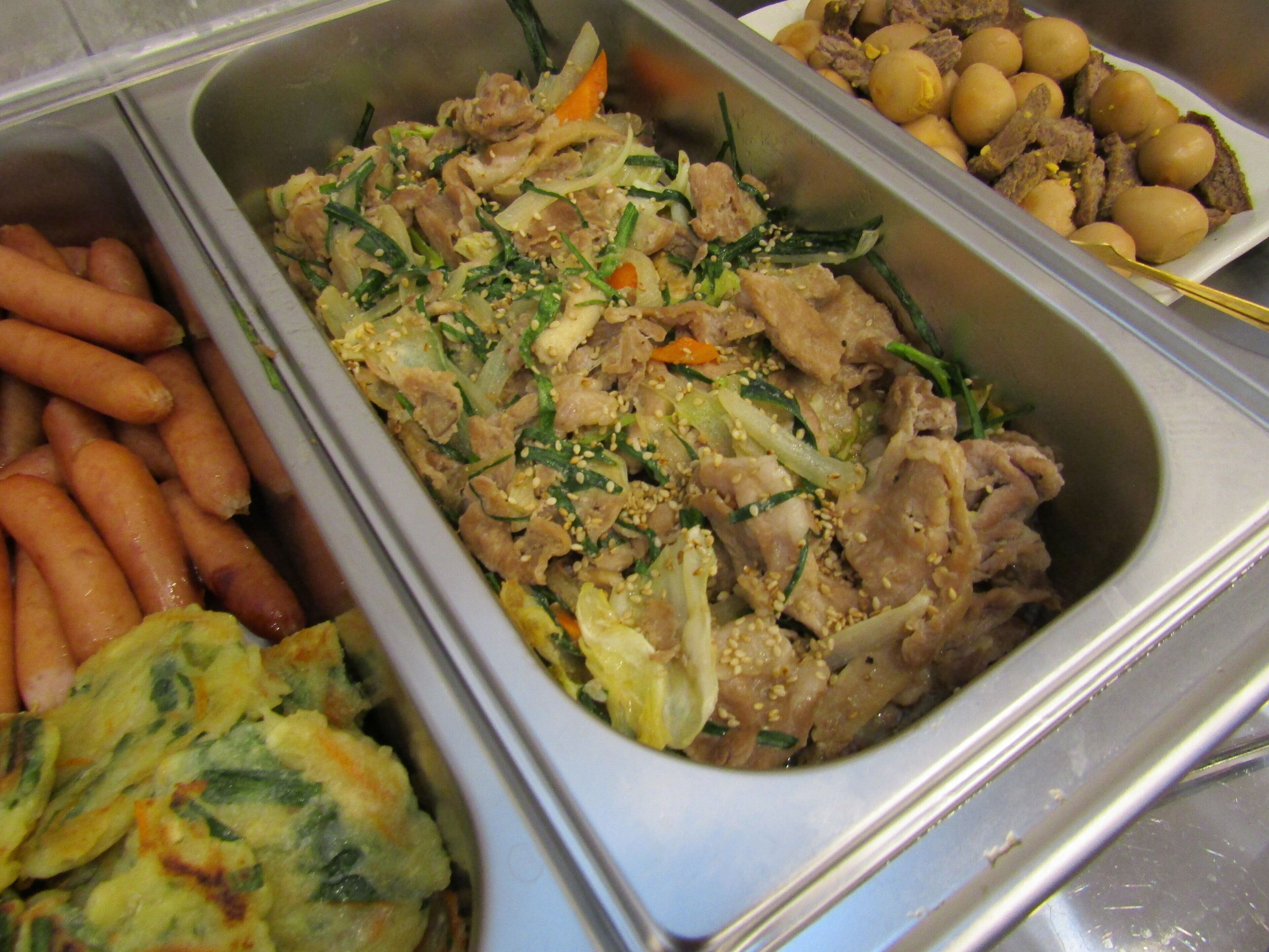 A buffet with various dishes including meat, vegetables, and a section with what appears to be fried items.