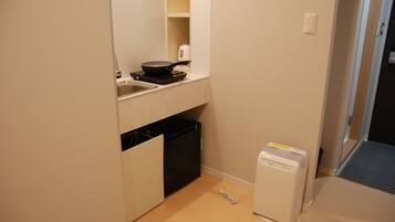 Una cocina pequeña con un lavamanos, estufa compacta y refrigerador pequeño.