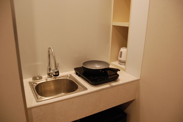 A compact kitchen with a stainless steel sink, a black electric stove, and a small countertop.