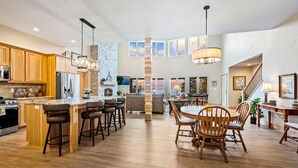 A spacious kitchen with wooden cabinets, a central island with bar stools, and a dining area with wooden chairs. - Northern Door County Waterfront Home (Sturgeon Bay)