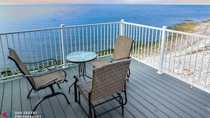 A wooden deck with wicker chairs and a glass table, overlooking a body of water. - Northern Door County Waterfront Home (Sturgeon Bay)